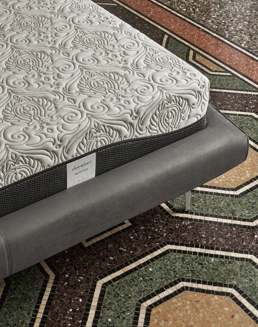 Close-up of the Dorelan ReStyle mattress featuring intricate stitching and a gray bed frame, placed on vibrant tiled flooring.