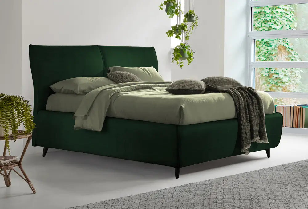 Elegante letto matrimoniale Dorelan modello Edward con rivestimento verde  intenso in velluto, arricchito da cuscini coordinati e una morbida coperta. Ambientato in una stanza luminosa con dettagli naturali, esprime uno stile sofisticato e un comfort senza tempo