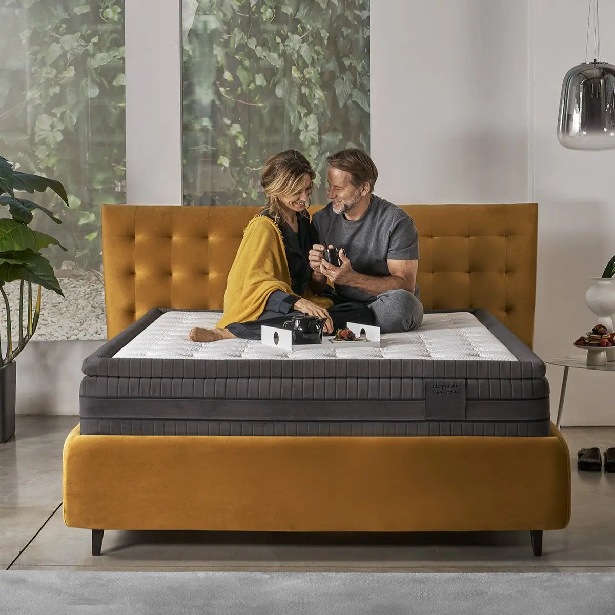 Couple sitting on Dorelan Tresor mattress, in an elegant and relaxing environment.