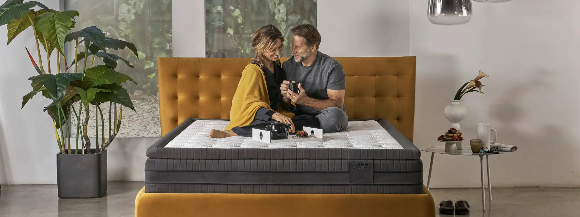 Smiling couple on Dorelan Tresor mattress, in cozy and modern environment.